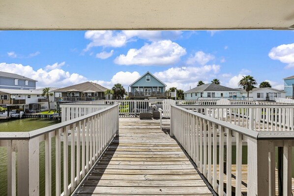 A wooden pier leading to a beachfront property with multiple houses and a boat dock.