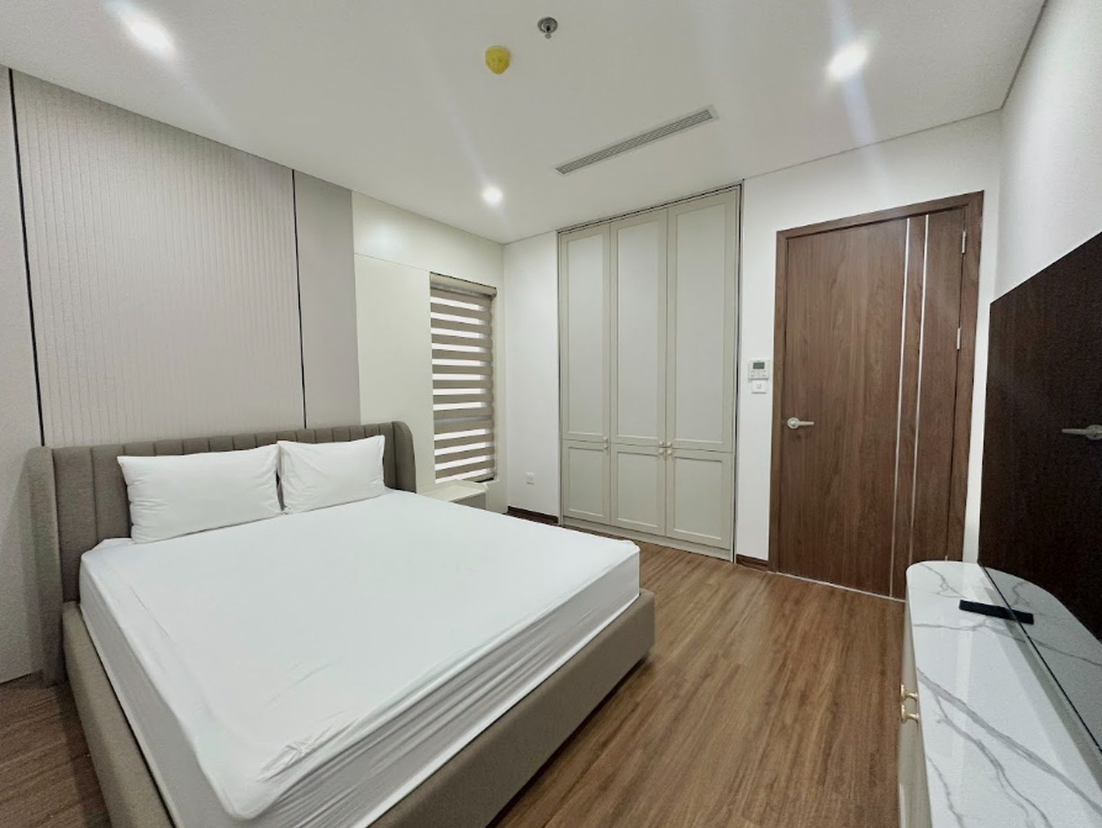 Un dormitorio con cama, armario y escritorio.