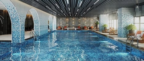 A large indoor swimming pool with a tiled floor, surrounded by seating areas and a modern ceiling design.