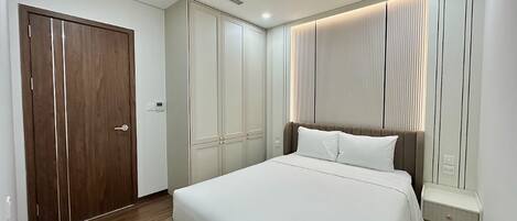 A hotel room with a large bed, a wardrobe, and a window with blinds.