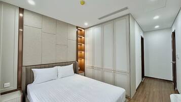 A hotel room with a large bed, built-in wardrobe, and a wooden floor.