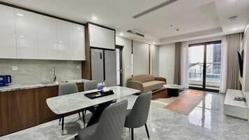 A modern hotel room with a dining area, a sofa, and a large window with a city view.