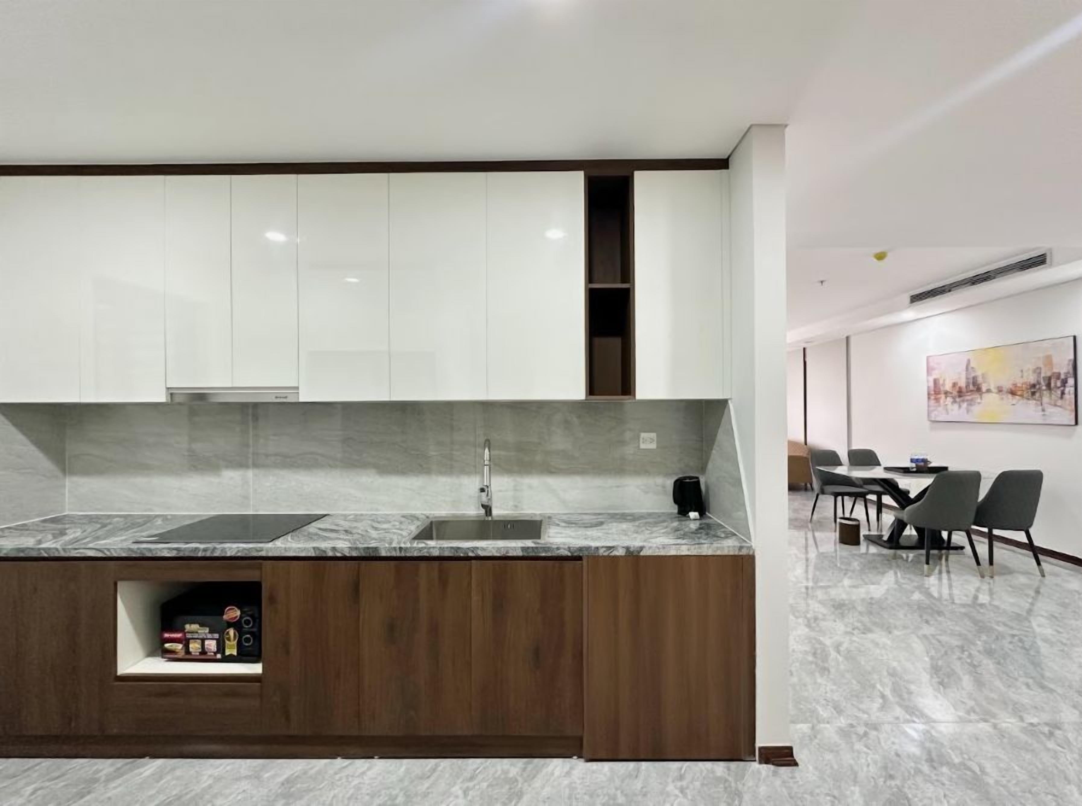 A modern kitchen with a marble countertop, wooden cabinetry, and a built-in sink.