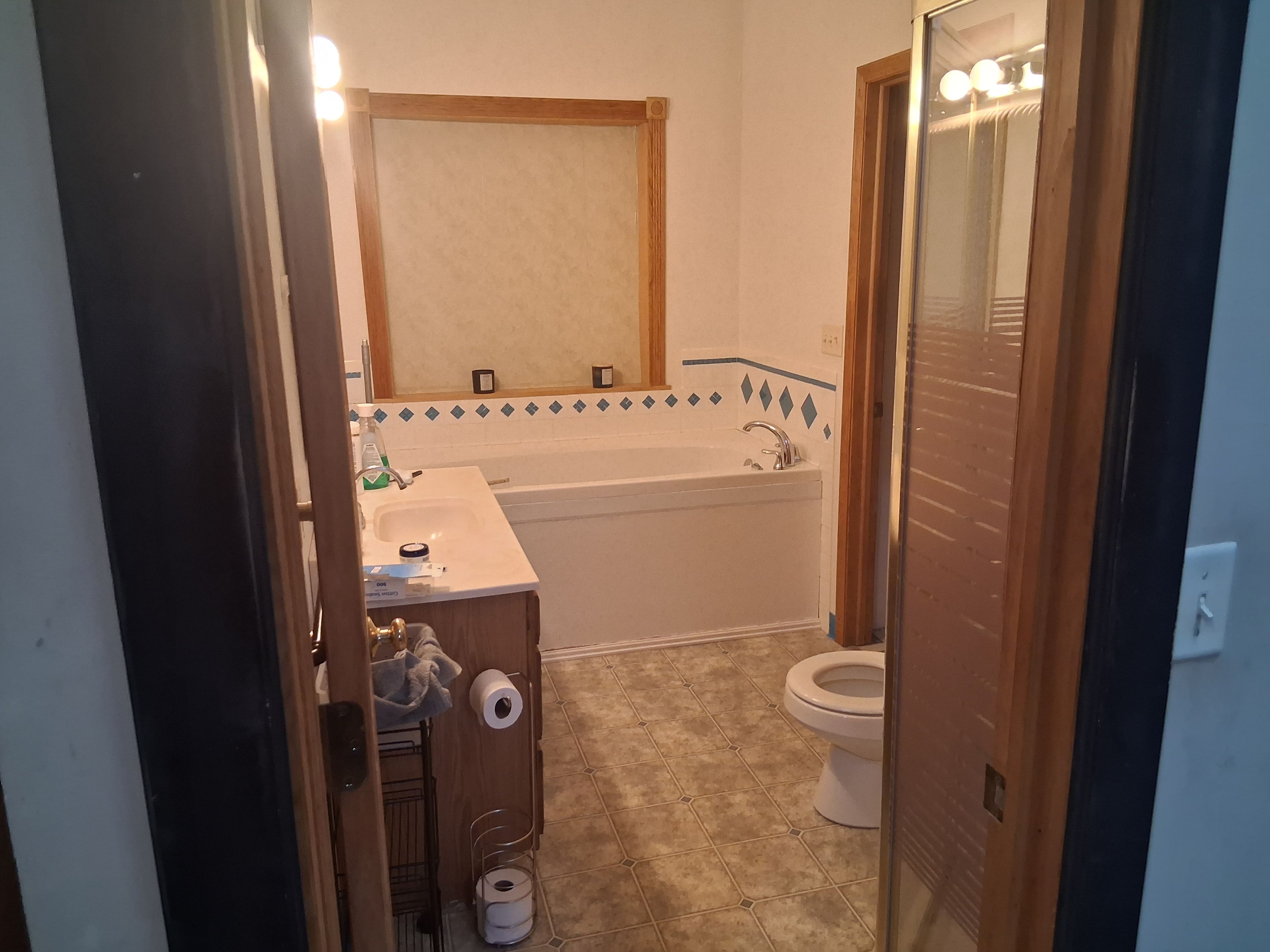 A bathroom with a bathtub, toilet, sink, and a mirror.