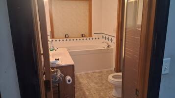 A bathroom with a bathtub, toilet, sink, and a mirror.