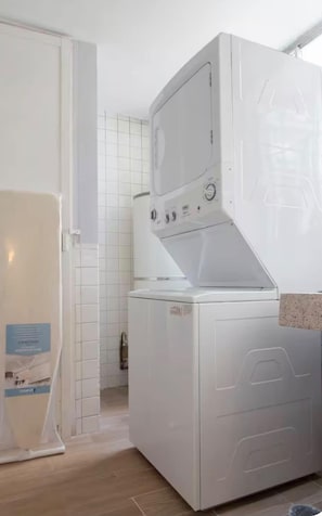 A compact, modern laundry room with a front-loading washer and dryer, a tiled backsplash, and a wooden floor. - Walk Polanco, luminous, safe, lots of space & love (Mexico City)