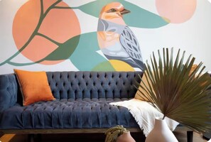 A room with a dark blue tufted sofa, an orange cushion, a white throw, and a large green plant in a white vase. - Walk Polanco, luminous, safe, lots of space & love (Mexico City)
