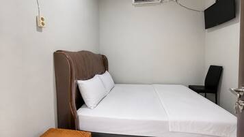 A single bed with a headboard, a bedside table with a remote control, a chair, and an air conditioning unit mounted on the wall.