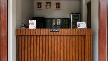 A reception desk with a wooden finish, a sign labeled 'RECEPTIONIST,' and three framed pictures above it.