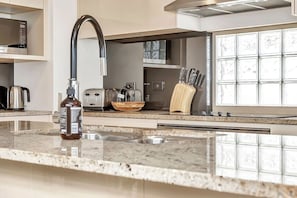 A modern kitchen with a stainless steel range hood, a built-in oven, a toaster, and a knife block. - Ochre Point Beach House, Moana-Seafront (Moana)