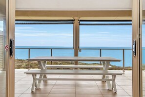 A white picnic table with a view of the ocean through a glass door. - Ochre Point Beach House, Moana-Seafront (Moana)
