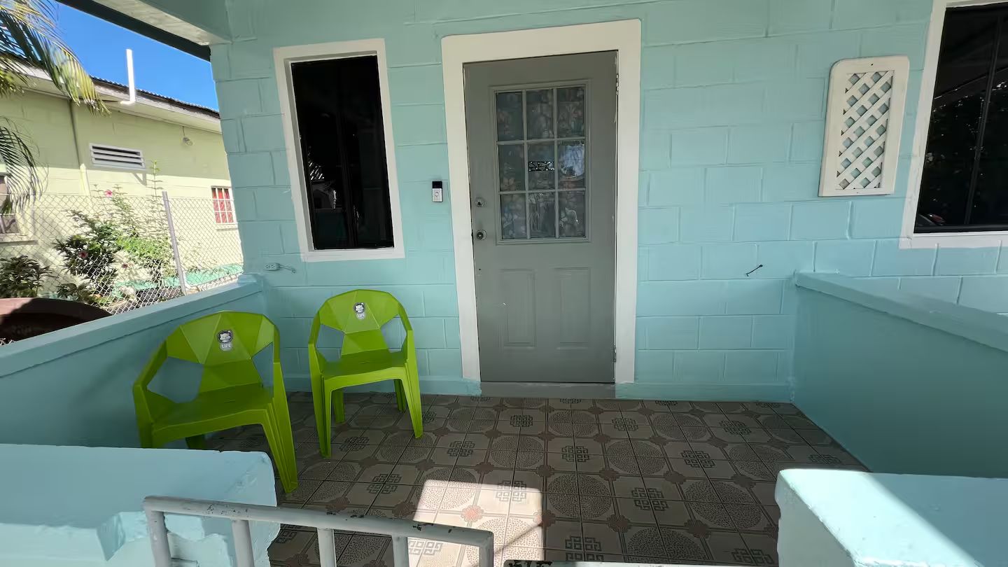 A room with a door, two green chairs, and patterned floor tiles.