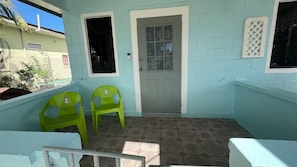 A room with a door, two green chairs, and patterned floor tiles.