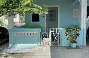 A light blue building with a gated entrance, a small window, and a potted plant. - Caribbean Cozy Cottage in Plymouth Village (Plymouth)
