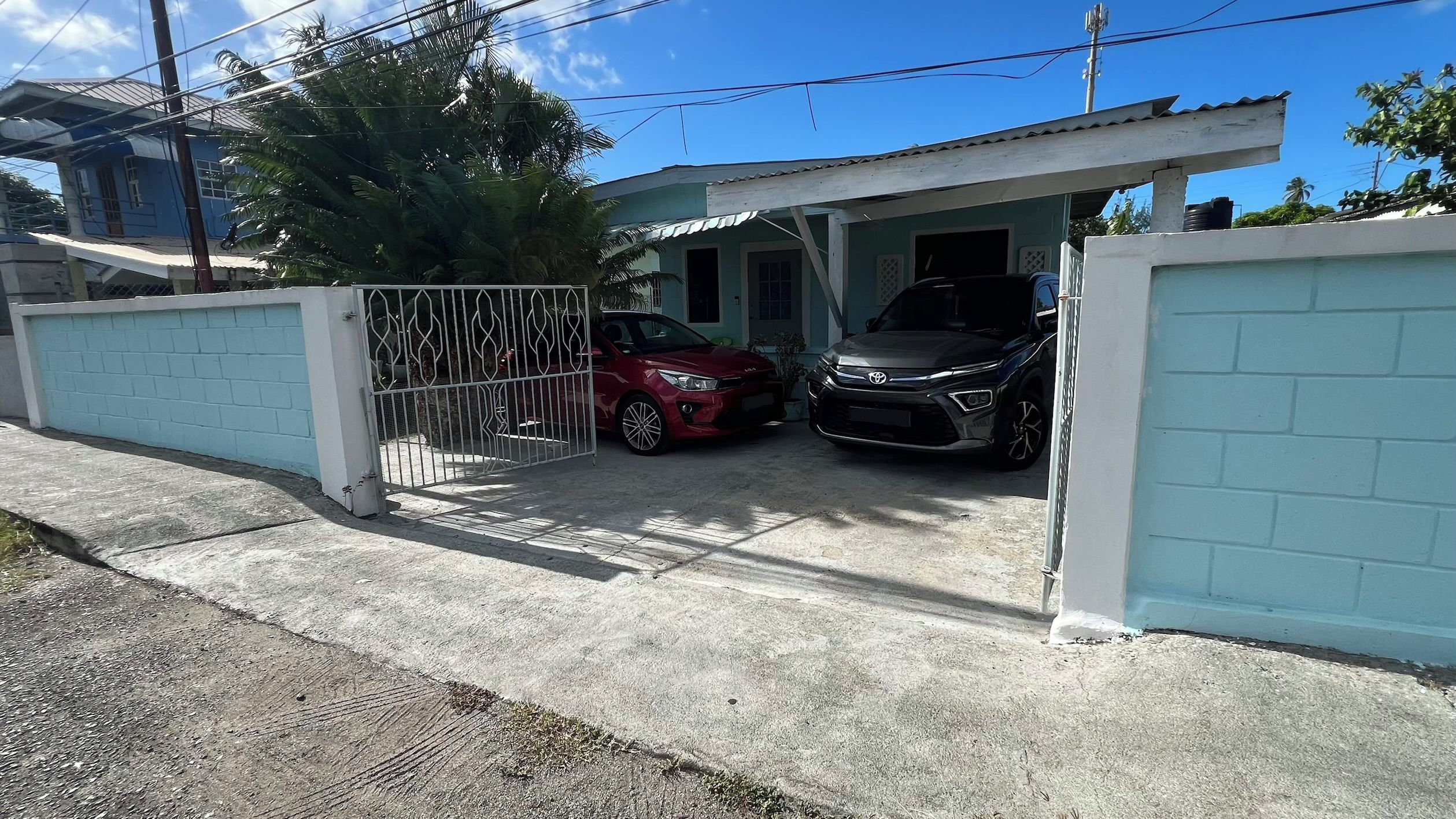A gated residential area with two cars parked in a driveway.