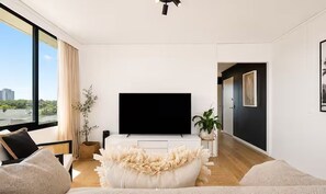 Una sala de estar moderna con un televisor de pantalla plana, un sofá, una mesa de centro y una planta en maceta.