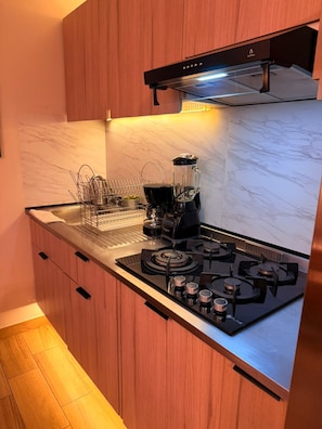 Una cocina moderna con estufa a gas, cafetera y licuadora sobre la encimera.