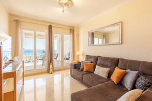 A living room with a large brown sofa, a mirror, and a view of the sea through the glass doors. - Manilva Playa with Sea view for 5, Manilva, Spain (Manilva)