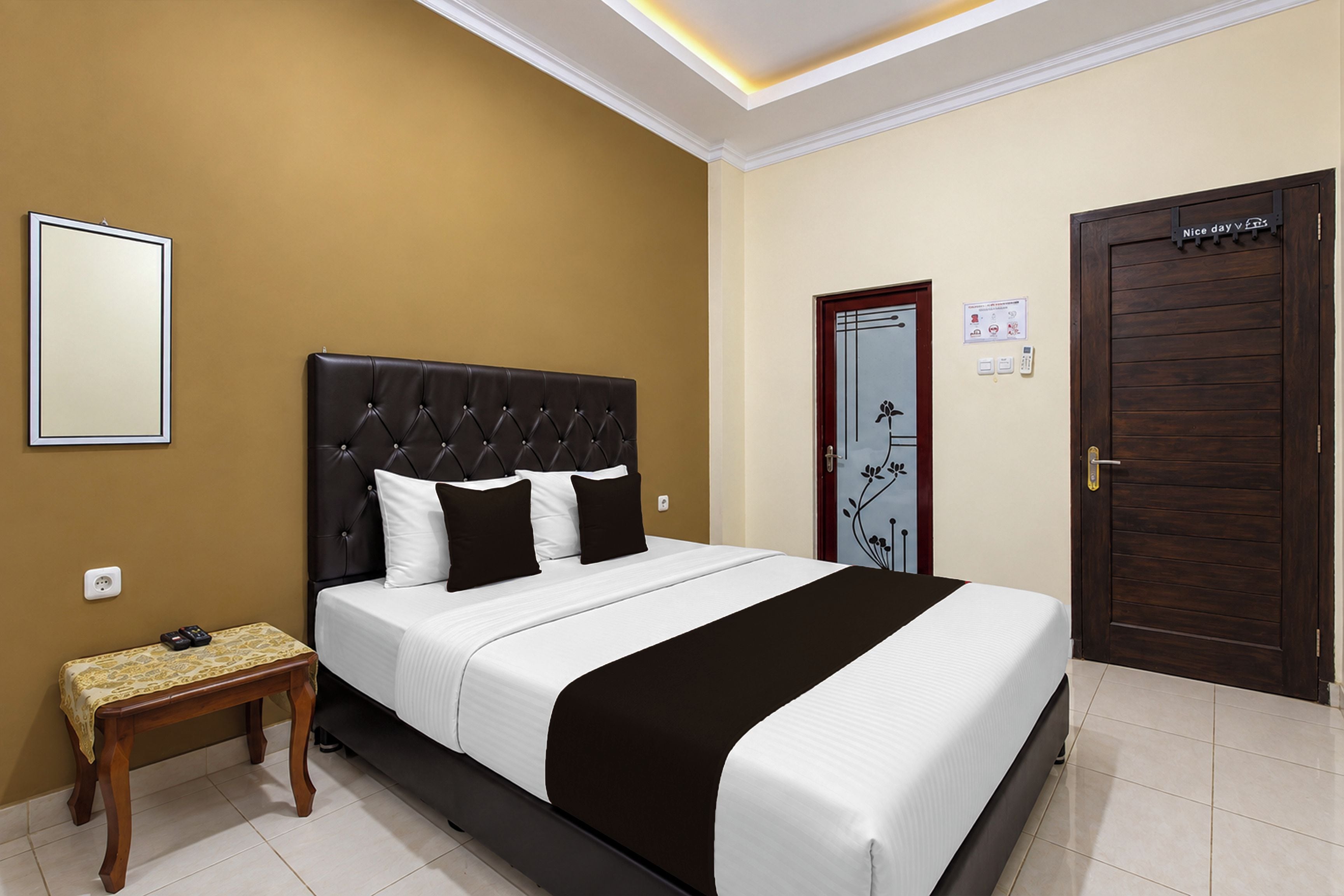 A hotel room with a bed, bedside table, and a door.