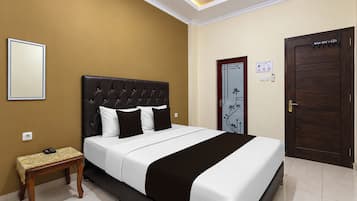 A hotel room with a bed, bedside table, and a door.