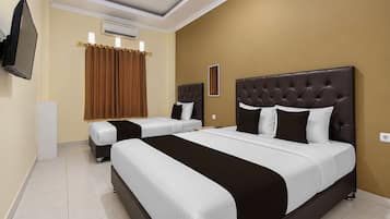 Een hotelkamer met twee bedden, een flatscreen televisie, een airconditioning en een raam met gordijnen.