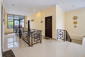 A hotel lobby with a reception desk, a staircase, and a door marked with the number 8. - Hotel O near Monumen Jogja Kembali (Ngaglik)