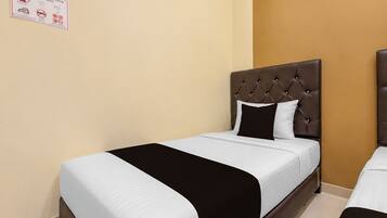 Ein Hotelzimmer mit einem Einzelbett, das ein gepolstertes Kopfteil und eine schwarz-weiß gestreifte Bettdecke hat.