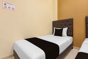 A hotel room with a single bed featuring a tufted headboard and a black and white striped bedspread. - Hotel O near Monumen Jogja Kembali (Ngaglik)