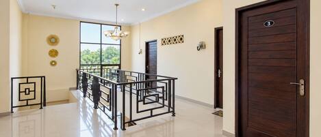 A spacious interior with a modern staircase, a large window offering a view, and a dark wooden door.