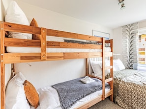 A bunk bed with wooden frames, white bedding, and a gray throw blanket.
