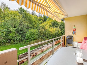 Ein Balkon mit Tisch und Stühlen, einem Geländer und Blick auf einen üppigen Garten.