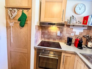 Eine Küche mit Holzsäulen, einem Herd, einem Backofen, einer Mikrowelle und einer Uhr an der Wand.