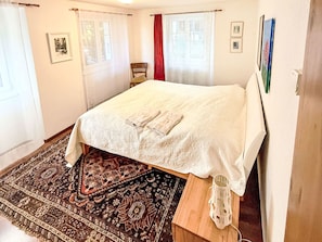A bedroom with a bed, a rug, a chair, and a window with curtains. - Chalet Bärgheimet by Interhome (Saas-Fee)