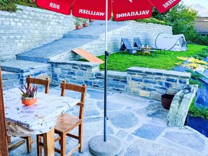 A patio with a table and chairs, a stone wall, and a tent. - Petit chalet du leigier by Interhome (Mase)