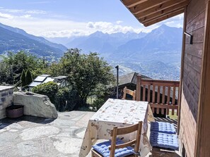 A wooden deck with a table and chairs, overlooking a mountainous landscape. - Petit chalet du leigier by Interhome (Mase)