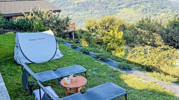 Et 'HIGHPEAK' telt er slået op på en græsplæne med et bord og stole i nærheden.