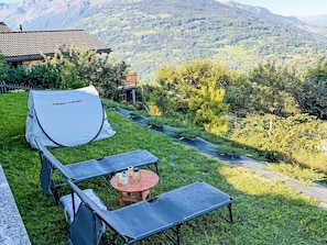 A tent labeled 'HIGHPEAK' set up on a grassy lawn with a table and chairs nearby.