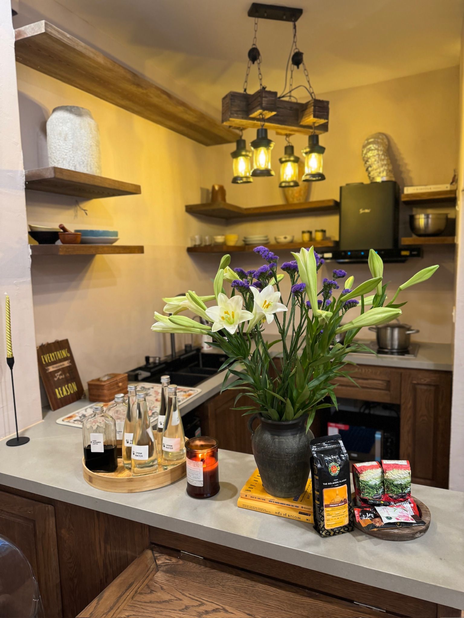A kitchen counter with a variety of items including a flower arrangement, bottles, and food products.