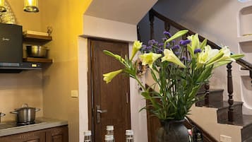 A kitchen with a coffee machine, a vase with flowers, and bottles of beverages on the counter.