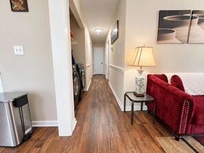 A hallway with a red sofa, a lamp, and a washing machine. - Cozy 3-bedroom Rocky Mount Home Retreat With Full Kitchen & Fenced Yard (Rocky Mount)