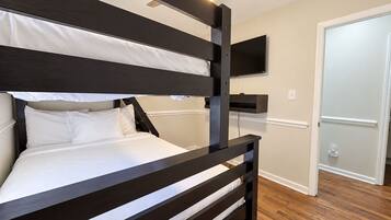 A bunk bed with a ceiling fan, a mounted TV, and a door leading to another room.