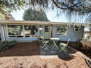 A house with a covered porch, a small table and chairs, and a garden area with mulch and plants. - Cozy midcentury home in South Eugene - 1 mi. to UO + walkable to cafes & trails (Eugene)