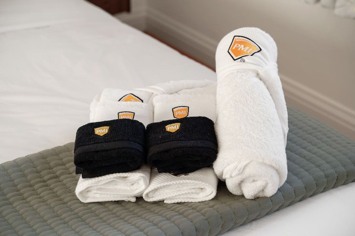 Una cama bien hecha con una colcha gris acolchada y una almohada blanca.
