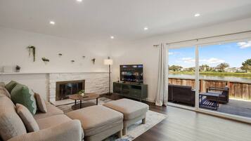 A living room with a fireplace, a television, and a view of a lake.