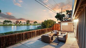 Un patio con mobiliario exterior, vista a un lago y una valla de madera.