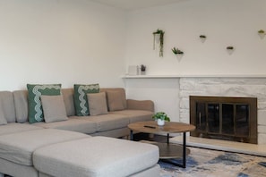 Una sala de estar con un sofá modular, una mesa de centro redonda y una chimenea.