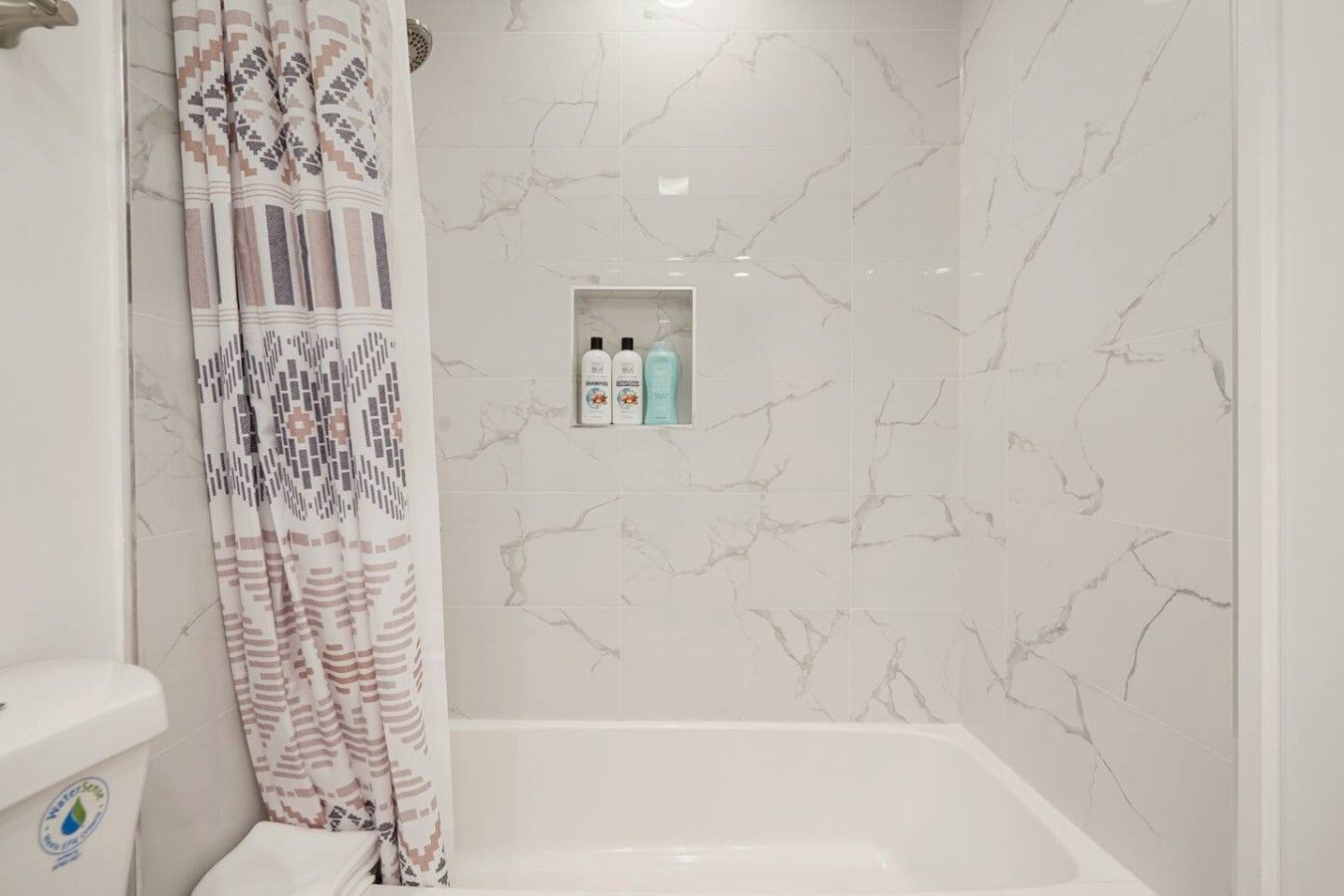 A bathroom with a bathtub, a shower curtain, and a shelf with toiletries.
