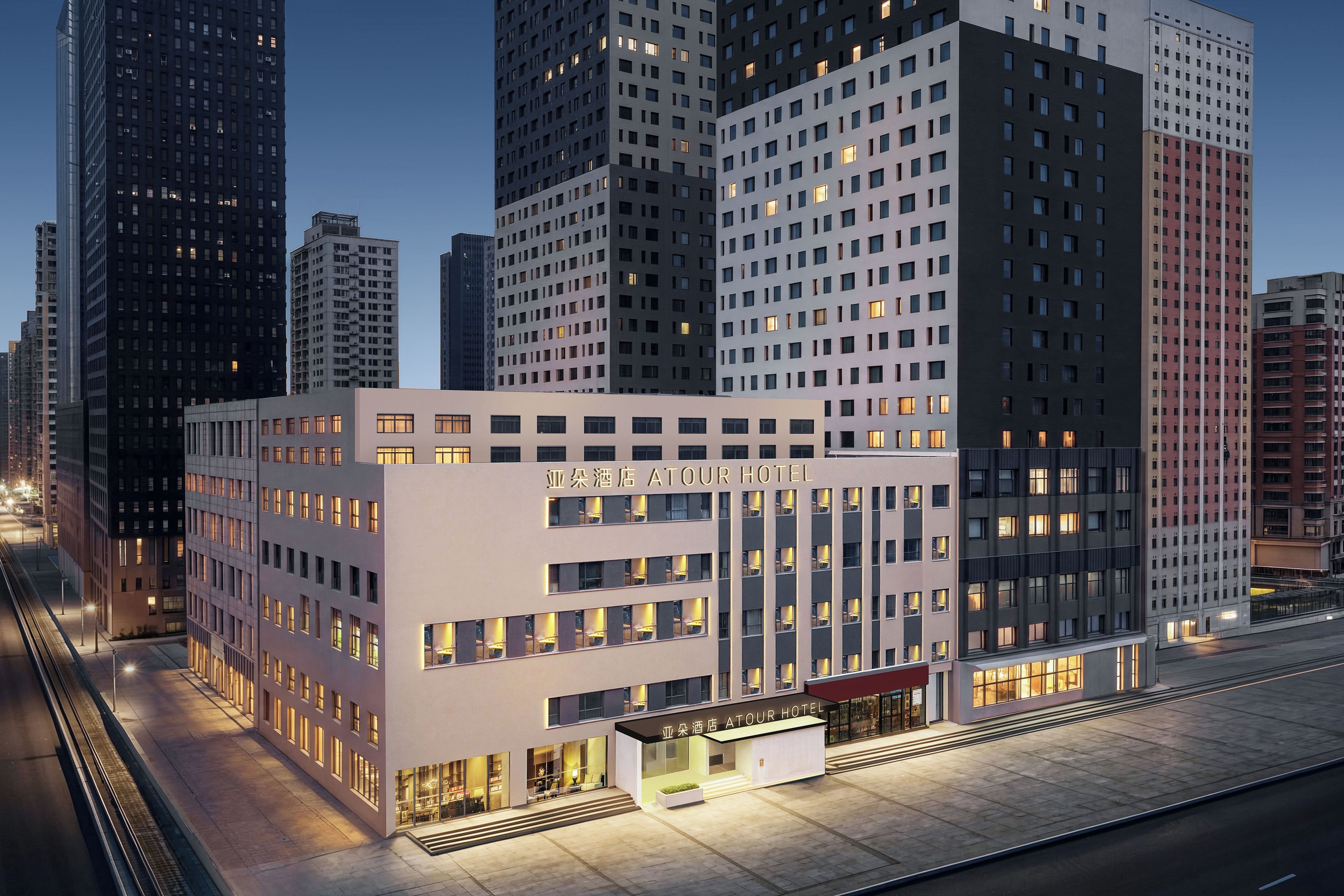 A modern hotel with a prominent entrance, multiple floors, and a view of surrounding high-rise buildings.