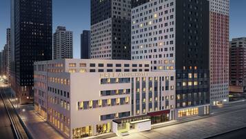 A modern hotel with a prominent entrance, multiple floors, and a view of surrounding high-rise buildings.