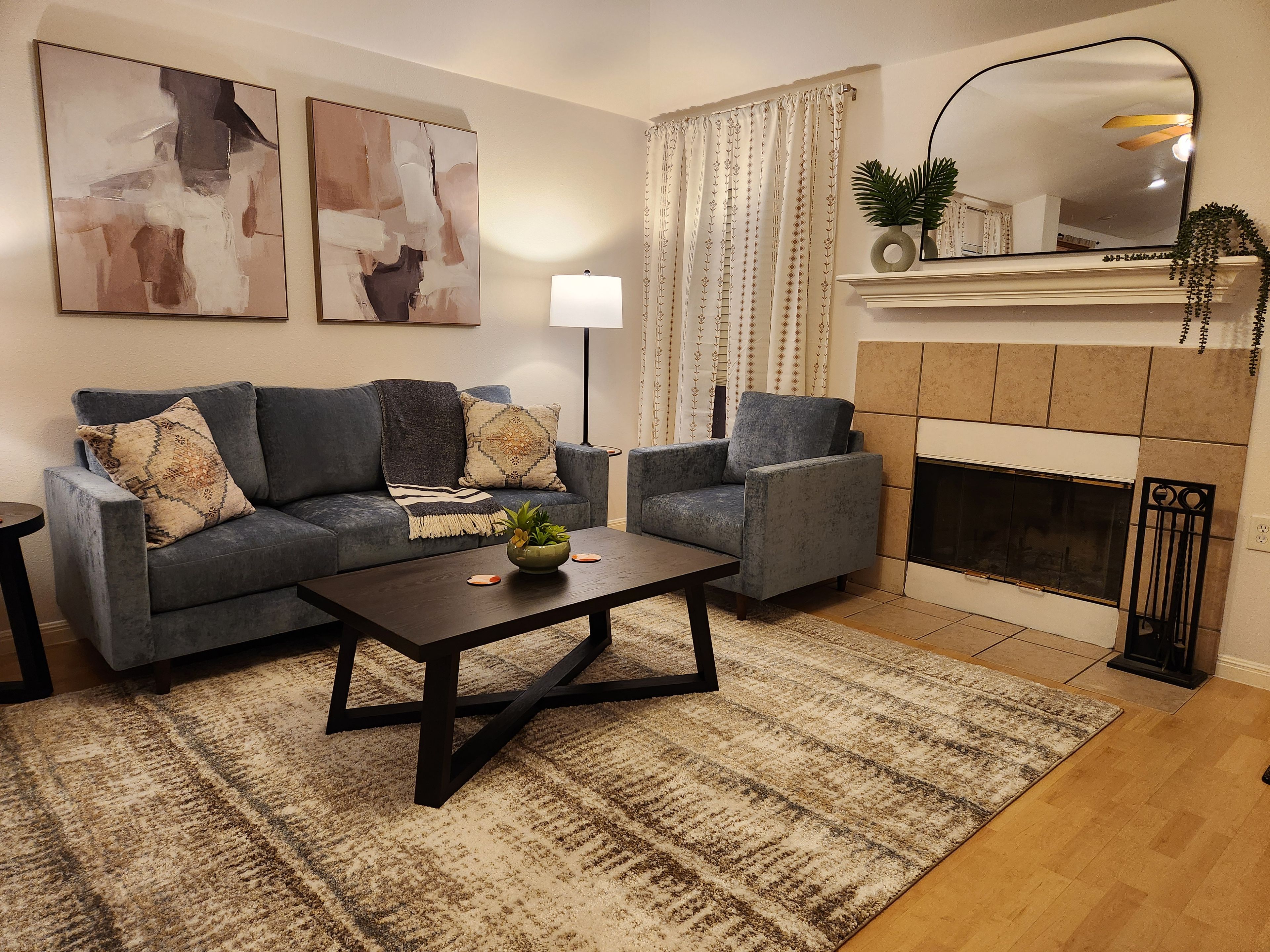 A living room with a sofa set, a coffee table, a fireplace, and abstract wall art.